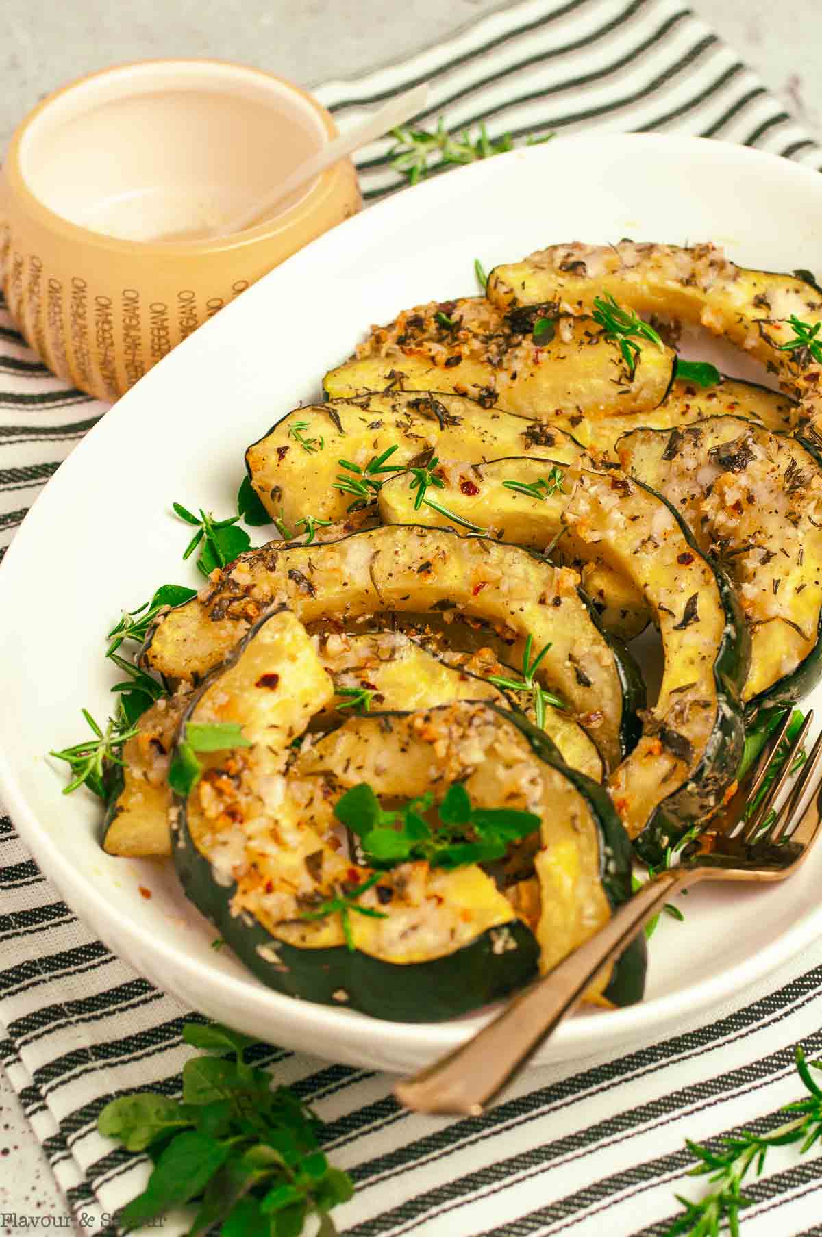 Slices of roasted acorn squash with garlic and parmesan on a white serving platter.