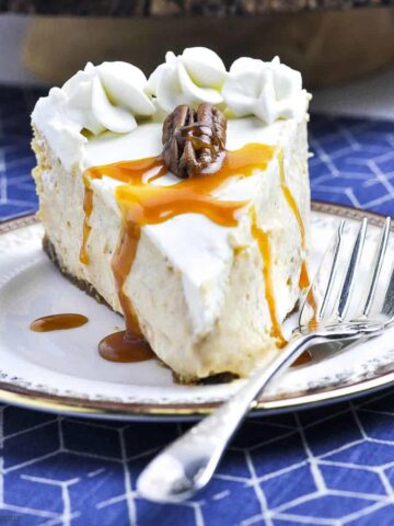 a slice of pumpkin cheesecake with caramel sauce and a pecan