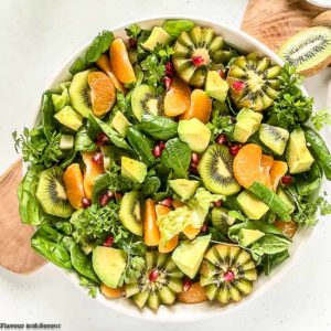 Overhead view of a bowl of Kiwi Mandarin Spinach Salad garnished with kiwi flowers