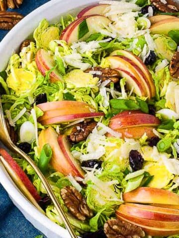overhead view of a bowl of shaved Brussels Sprout salad with sliced apples and pecans
