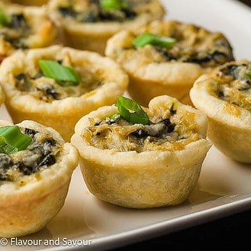 Closeup view of mini spinach artichoke tarts.