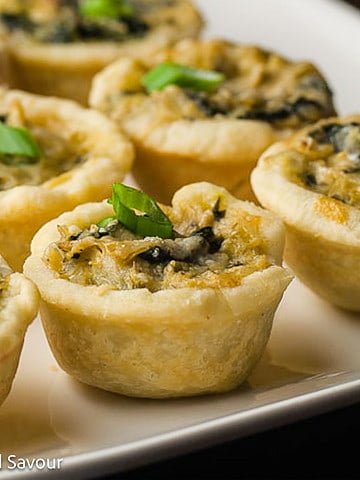 Closeup view of mini spinach artichoke tarts.