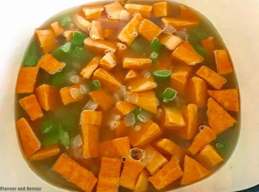 Adding  sweet potatoes and stock to corn chowder.