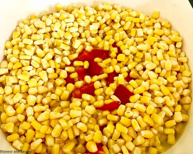 Adding  red pepper and corn to corn chowder.