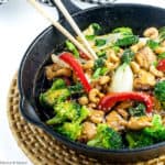 Chicken stir fry in cast iron pan with broccoli and red peppers