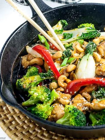 Chicken stir fry in cast iron pan with broccoli and red peppers