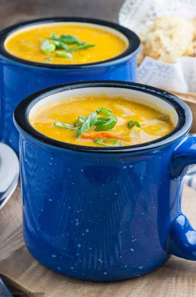 Close up view of Hearty Vegan Sweet Potato Corn Chowder in two blue mugs