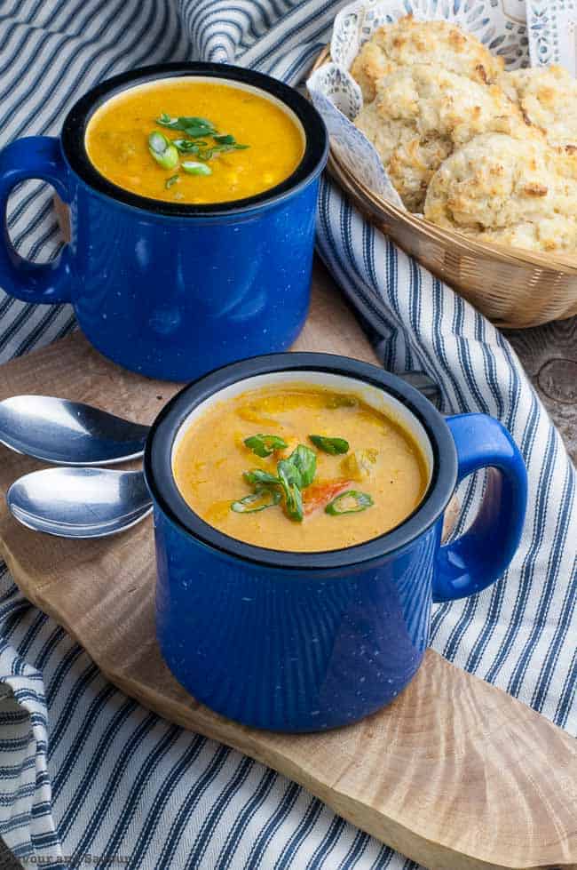 Hearty Vegan Sweet Potato Corn Chowder with turmeric in blue soup mugs