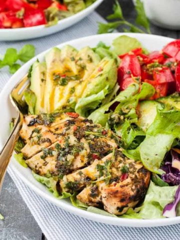 Close up view of Chimichurri Chicken Dinner Salad with mixed greens and sliced avocado