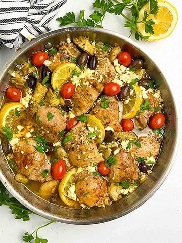 A skillet with baked lemon artichoke chicken.