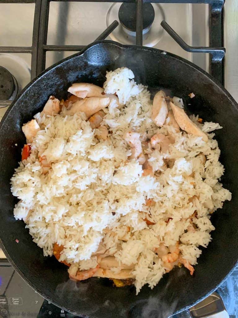 adding cooked rice to Nasi Goreng in a skillet