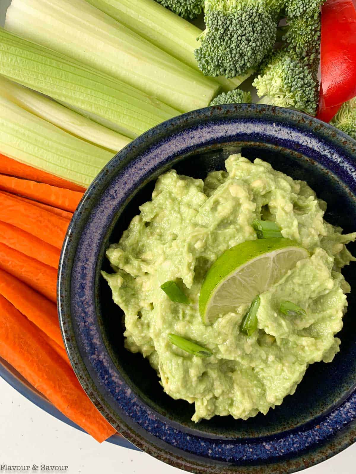 a bowl of guacamole with fresh veggie sticks