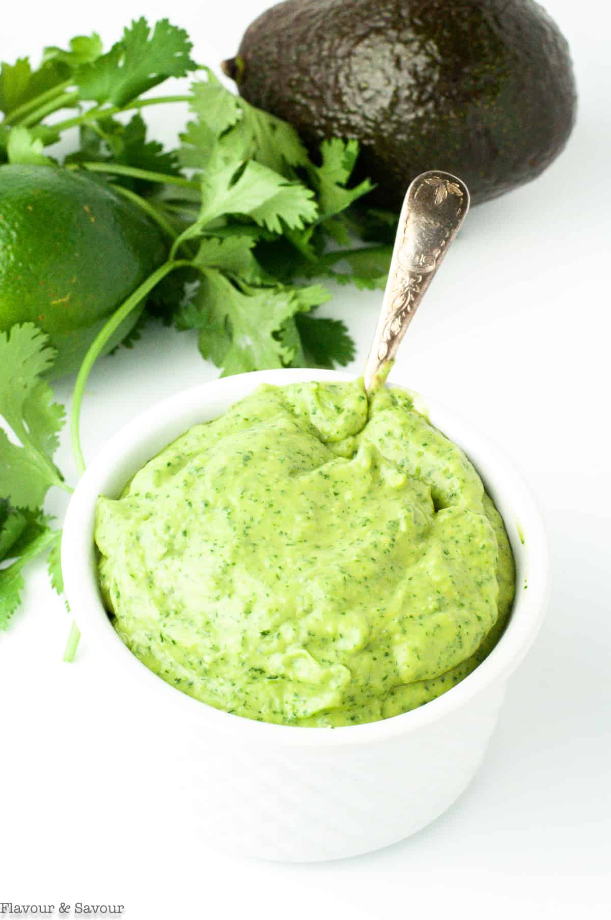 Avocado cream sauce in a small bowl with a spoon.