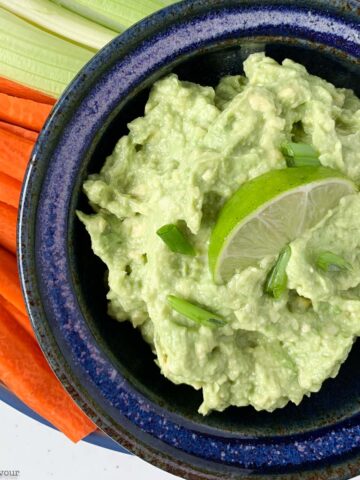 a bowl of guacamole with veggie sticks