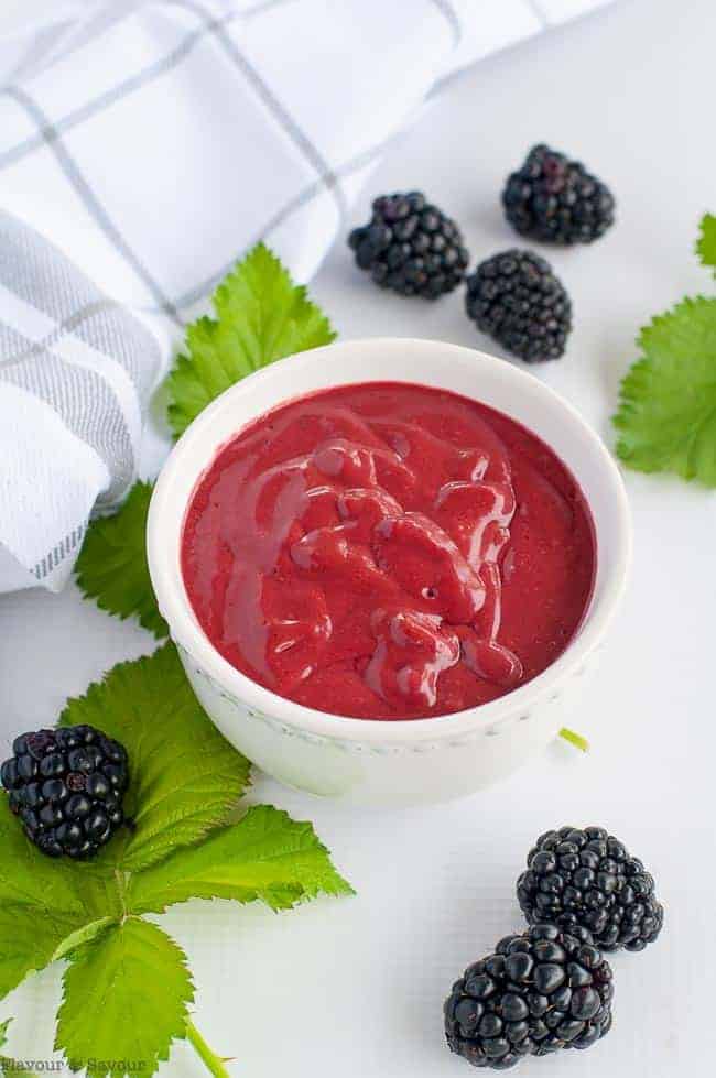 Blackberry Balsamic Dressing in a white bowl with fresh blackberries beside it.