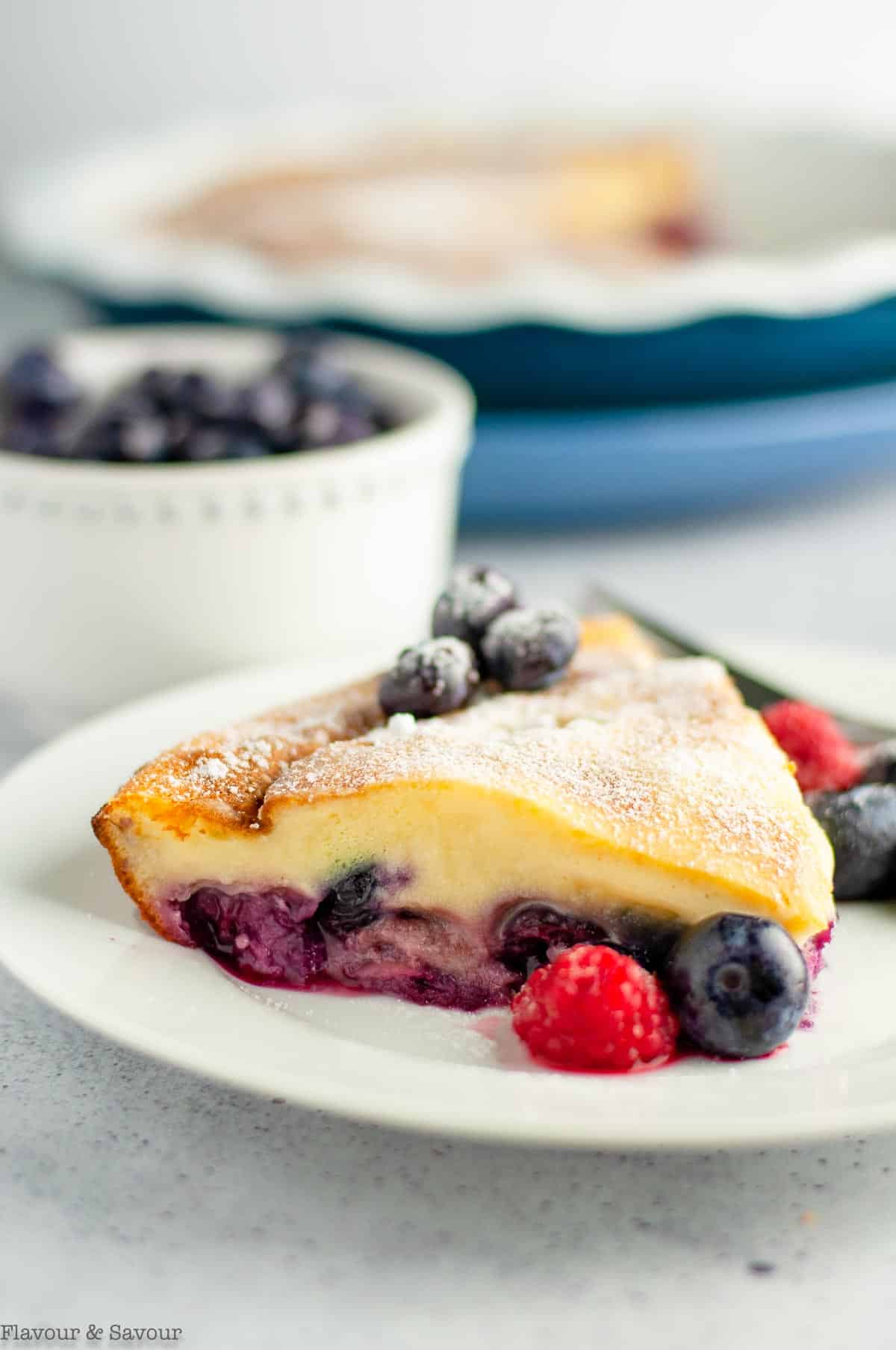 A wedge of clafoutis made with cherries and berries.