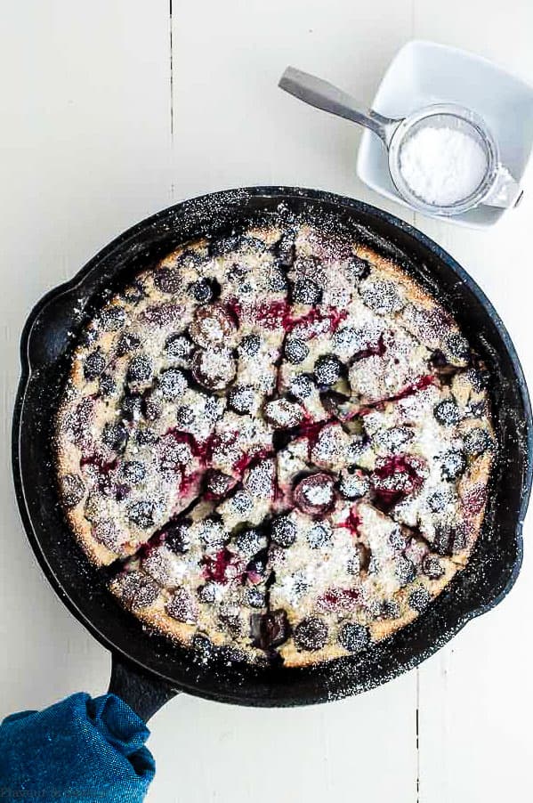 Cherry Berry Clafoutis in a skillet with confectioner's sugar