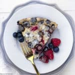 A slice of clafoutis on a white plate with a fork