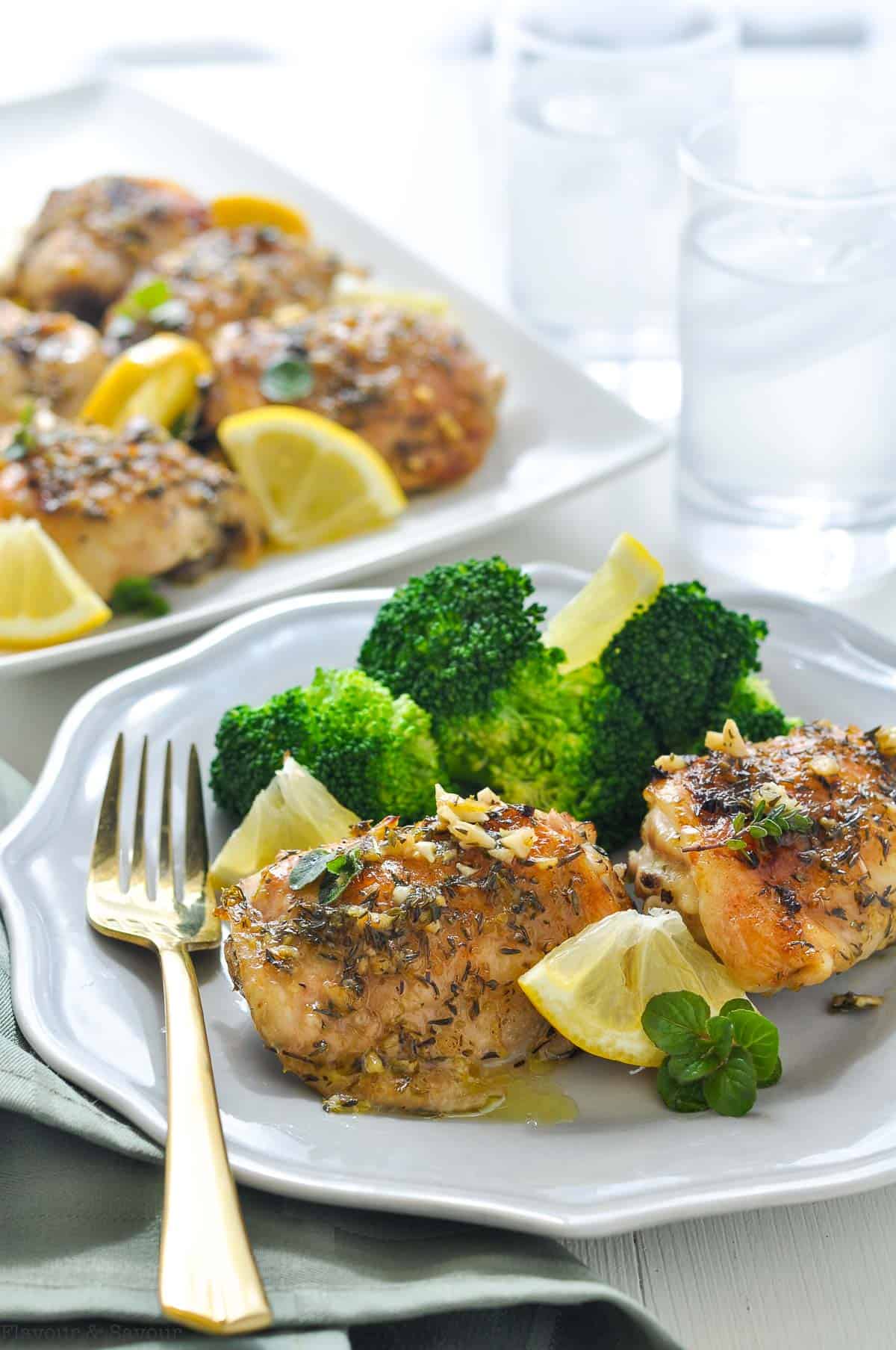 Easy Baked Lemon Chicken on a plate with broccoli and lemon wedges