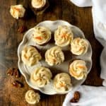 Mini Gluten-free Carrot Cake Cupcakes frosted with maple cream cheese frosting on a white cake plate.