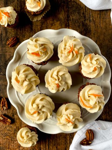 Mini Gluten-free Carrot Cake Cupcakes frosted with maple cream cheese frosting on a white cake plate.
