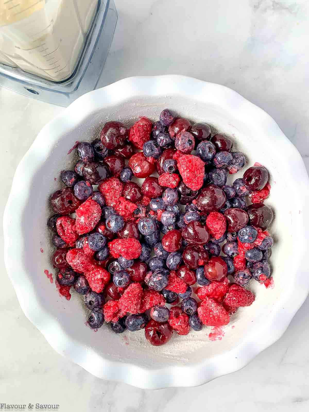 Cherries and berries in a baking dish as the first step to making a clafoutis.