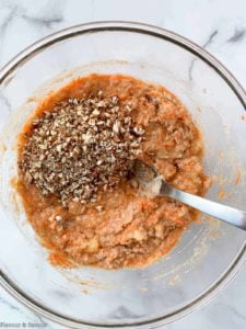 stirring chopped pecans into carrot cake batter