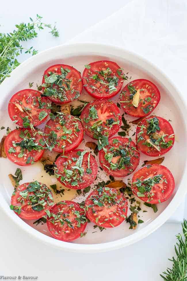 Tomato halves with garlic-infused oil and fresh chopped herbs.