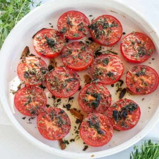 Broiled Italian Tomatoes in a white shallow dish