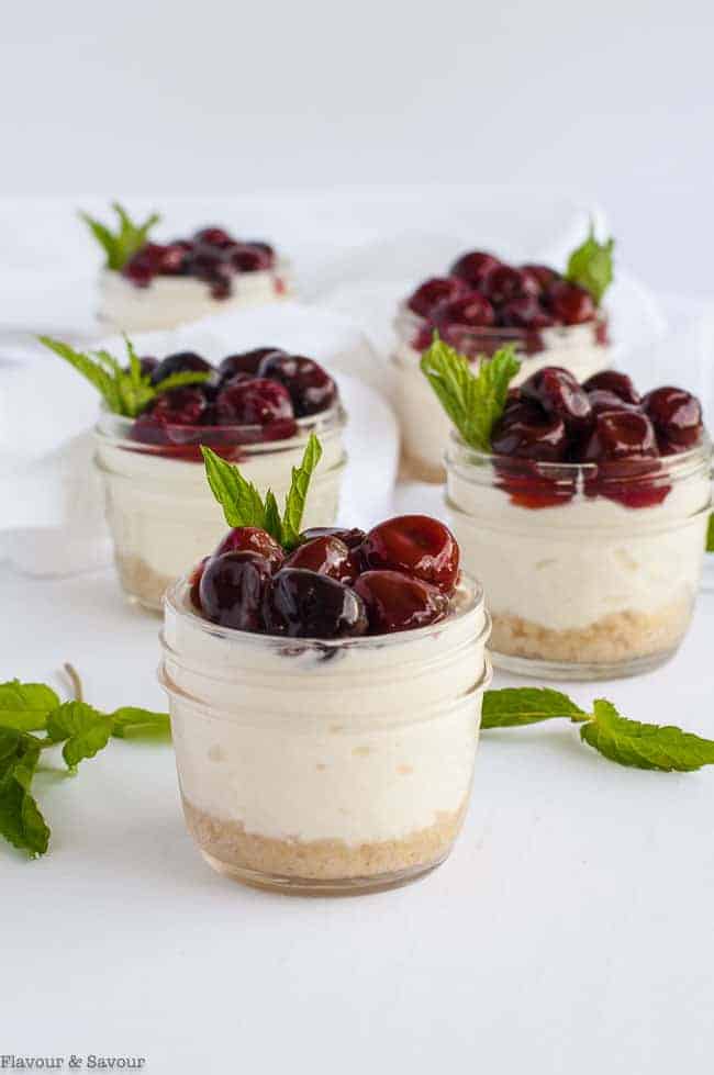 small jars filled with Cherry Cheesecake and garnished with fresh mint