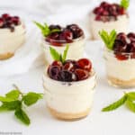 a group of mini no-bake cherry almond cheesecakes in small jars