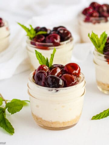 a group of mini no-bake cherry almond cheesecakes in small jars