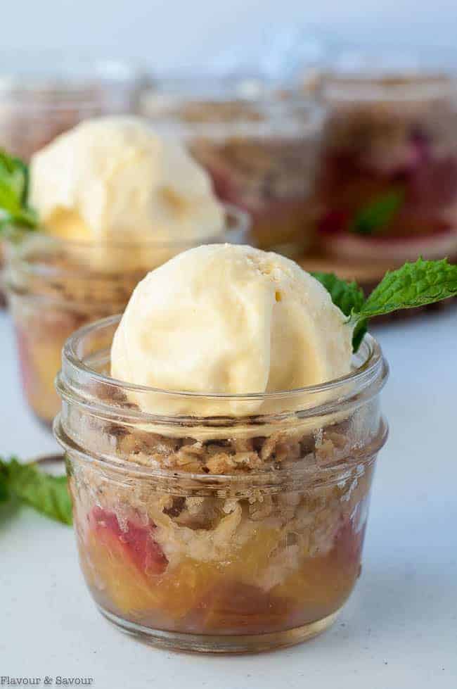 A small Mason jar with Pineapple Rhubarb Crisp and ice cream