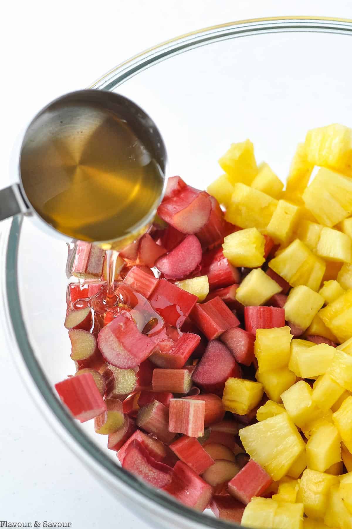 adding honey to pineapple and rhubarb in a bowl