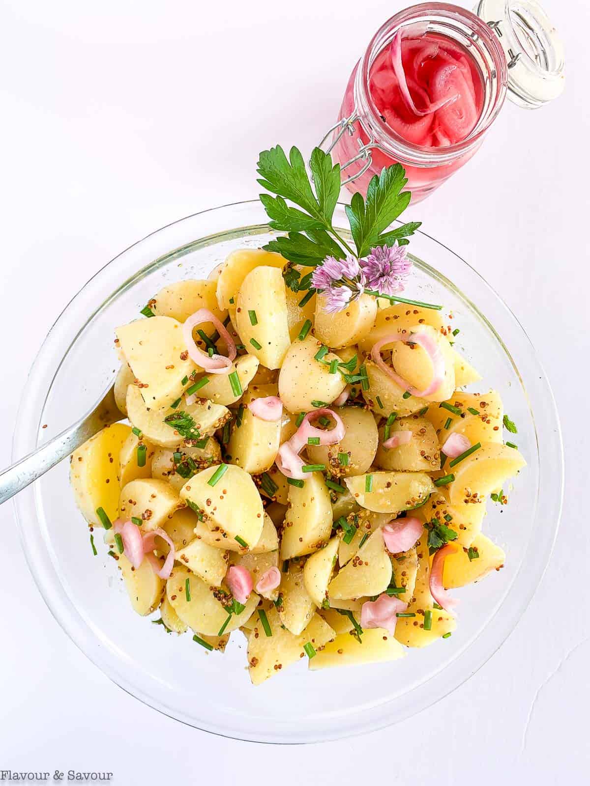 A bowl of Italian potato salad with a jar of pickled shallots beside