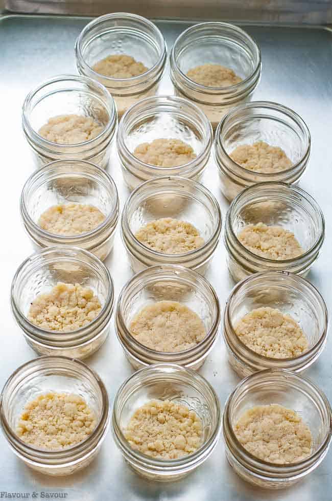 pressing the base for no-bake cheesecake into 12 mini Mason jars