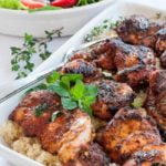 A serving dish full of Cajun chicken thighs on quinoa