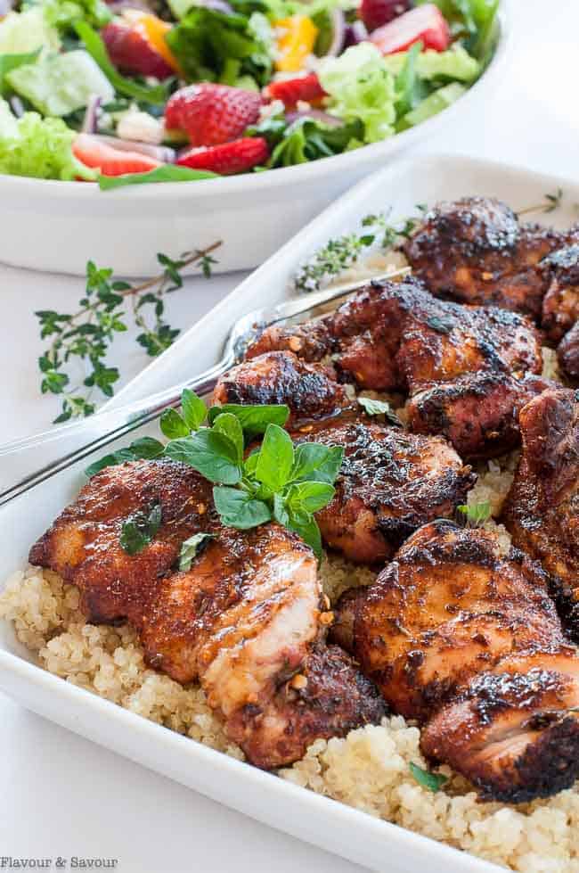 A serving dish full of Cajun chicken thighs on quinoa