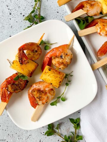 Grilled Cajun Prawn or Shrimp Skewers with pineapple on a small white plate