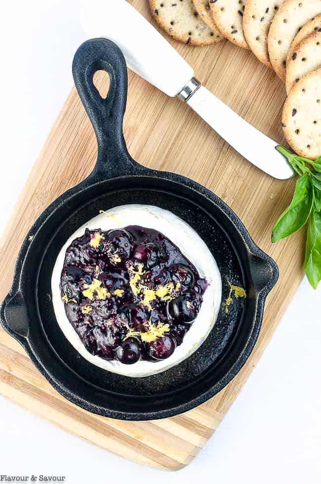 Blueberry Basil Chia Seed Jam on Brie in a small skillet with crackers and a knife