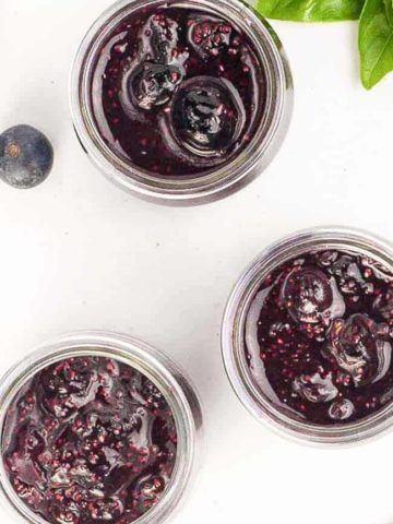3 jars of Blueberry Basil Chia Seed Jam with fresh basil leaves