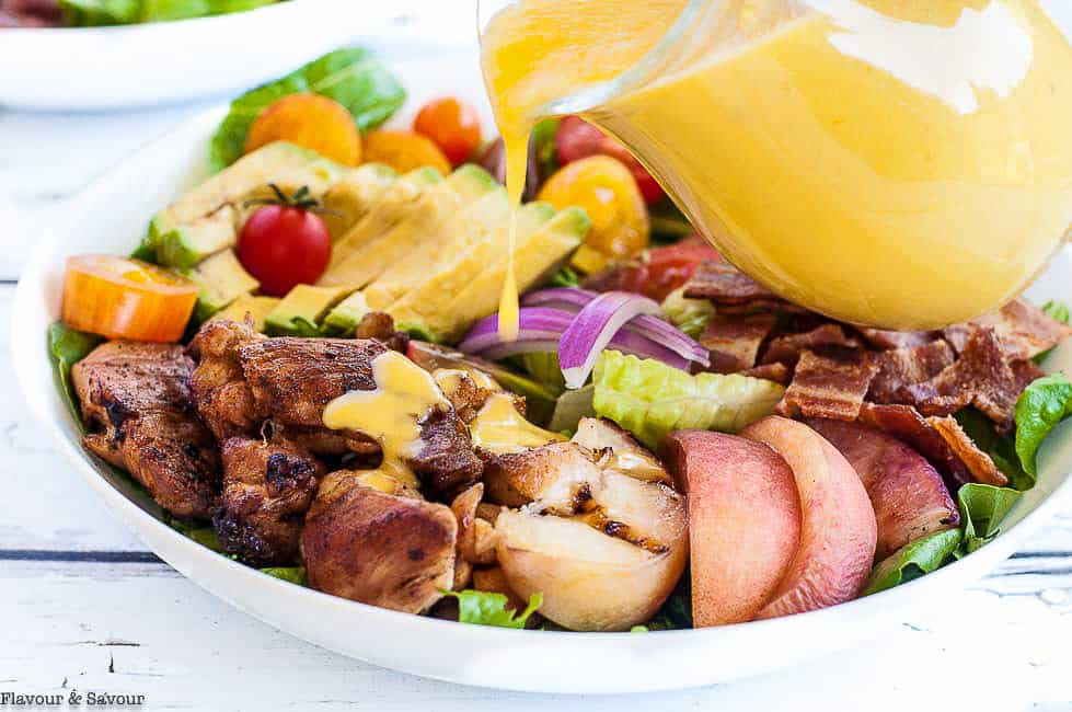 Pouring Peach dressing on Chipotle Chicken Cobb Salad