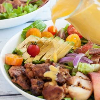 Pouring Sweet Peach Salad Dressing on a green salad