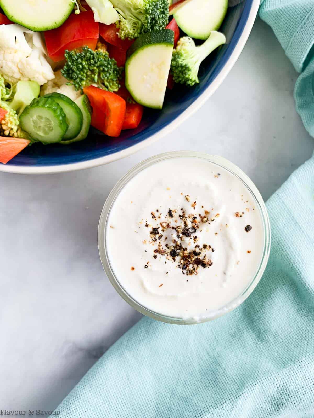 A bowl of yogurt feta dressing next to a bowl of veggies