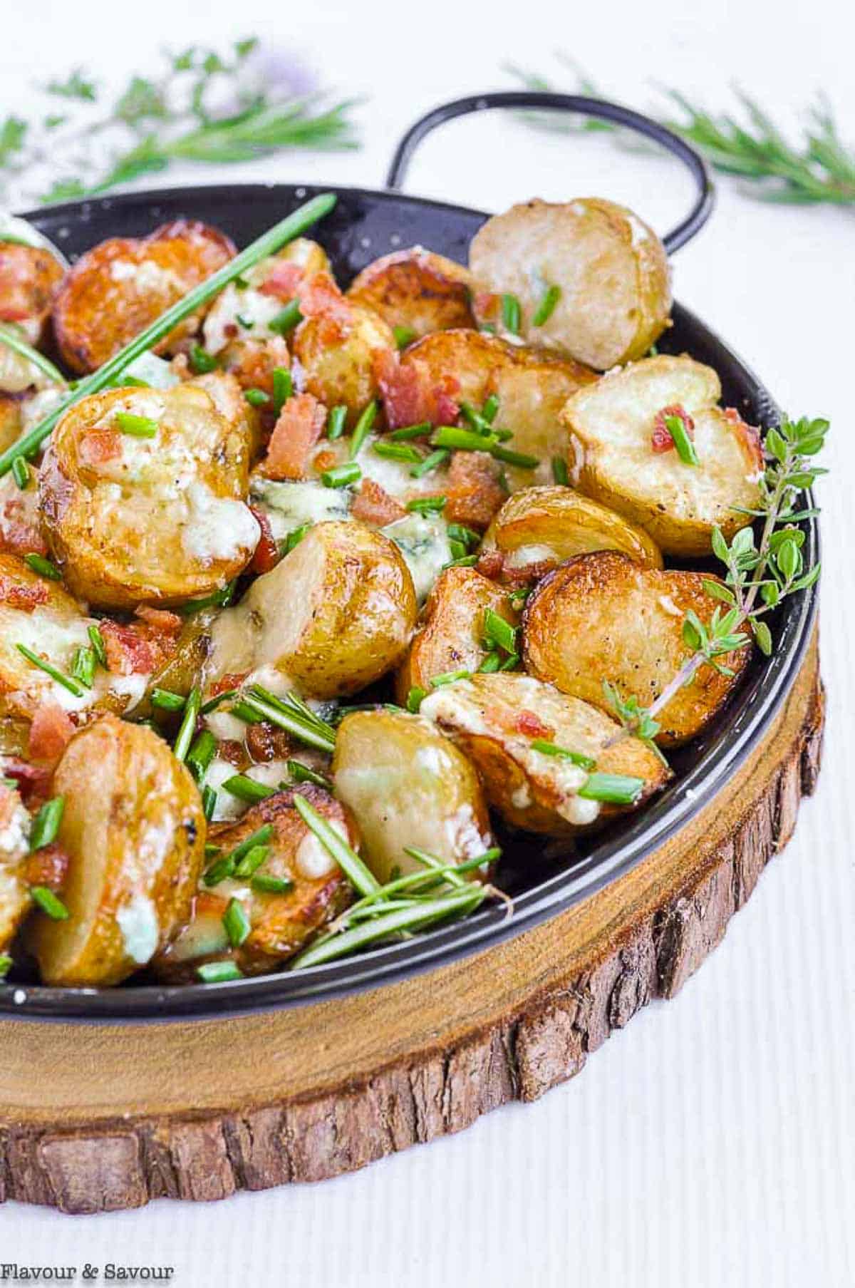 Close up view of grilled potatoes with cheese with fresh oregano and rosemary.