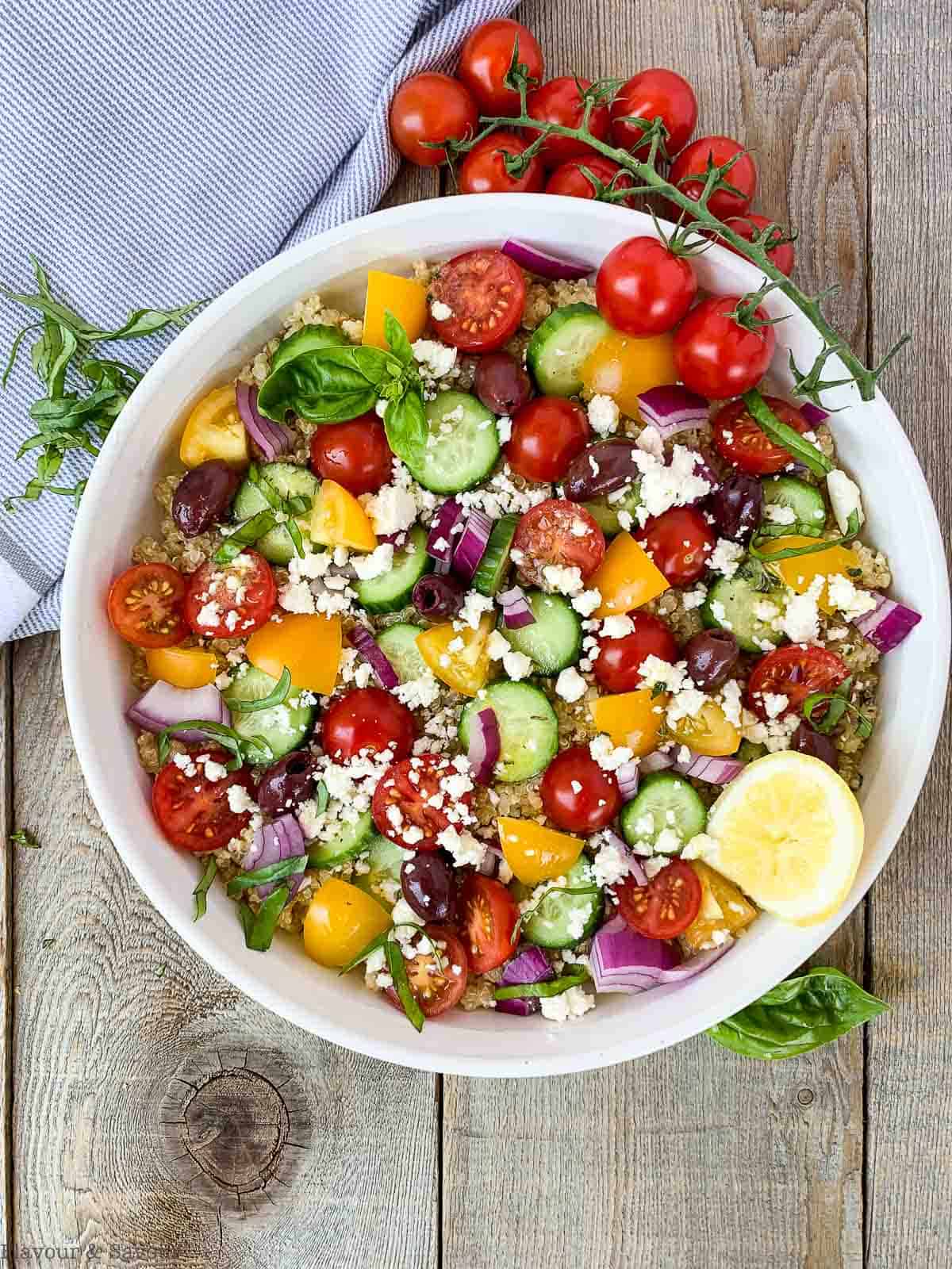 Mediterranean Quinoa Salad on a board with a sprig of cherry tomatoes