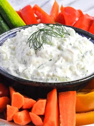 a bowl of Greek Tzatziki Sauce surrounded by fresh raw vegetables