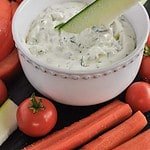 Dipping zucchini stick into Herbed Feta Dip with Lemon