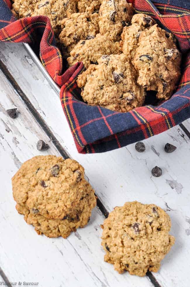 A metal basket and plaid cloth with gluten-free cherry chocolate oatmeal cookies