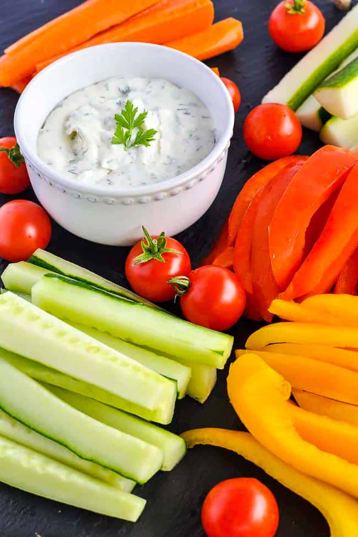 A bowl of feta dip with lemon and herbs surrounded by veggie sticks.